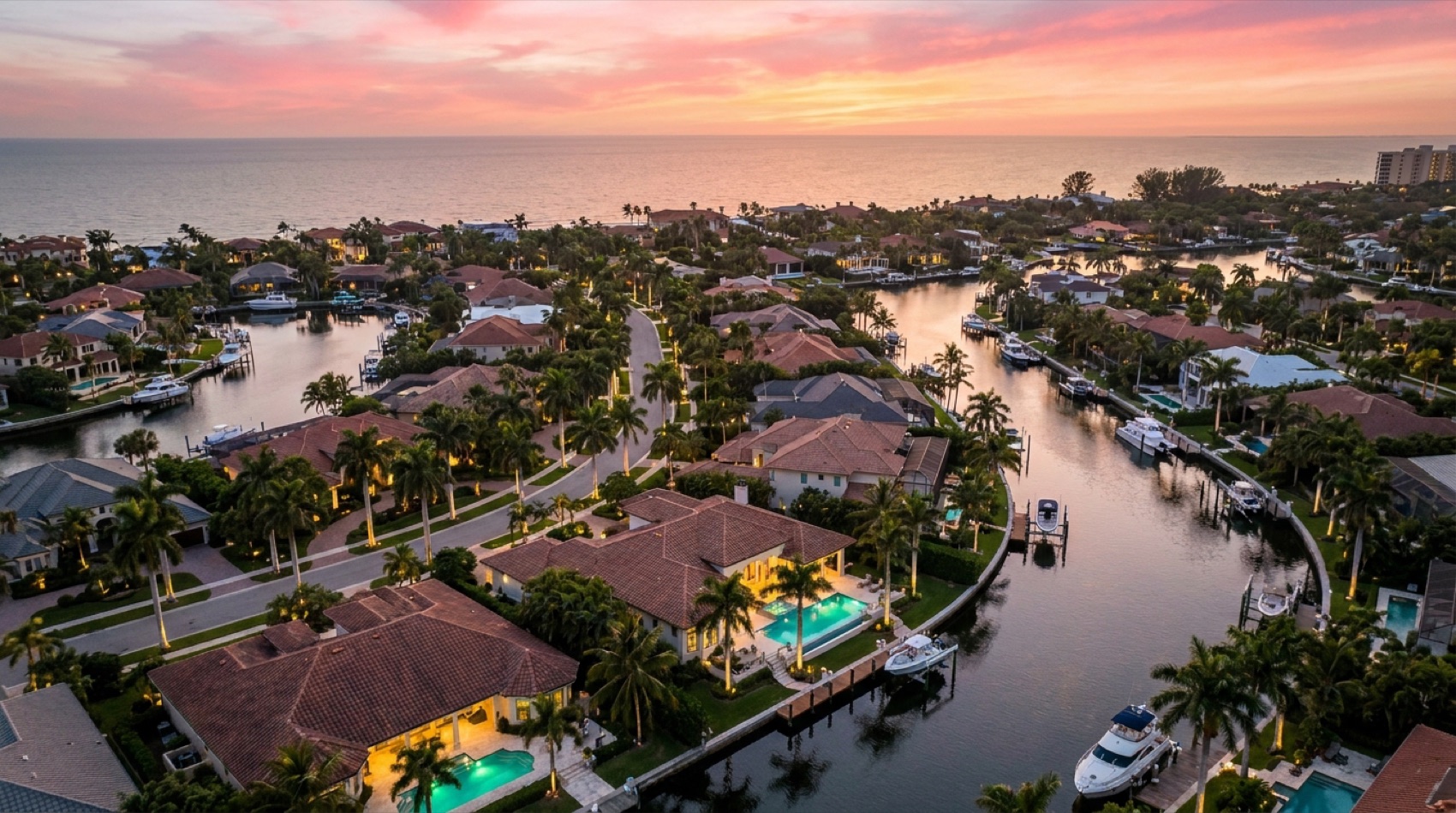 Aerial twilight view of a luxury Naples waterfront neighborhood with canals and pools