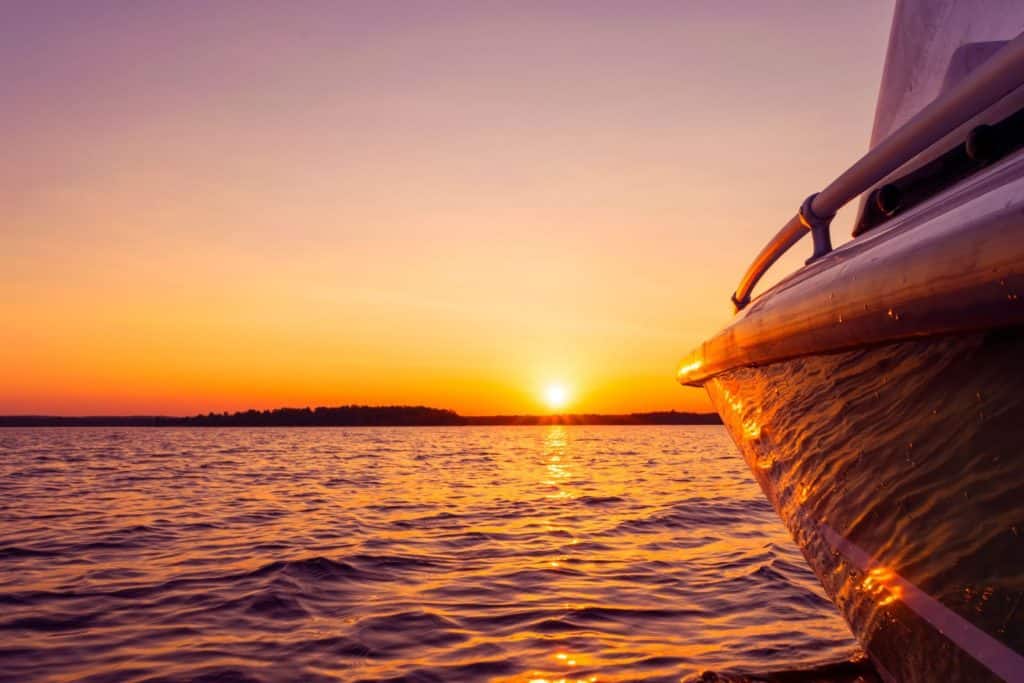 A view of an ocean sunset from the side of a boat